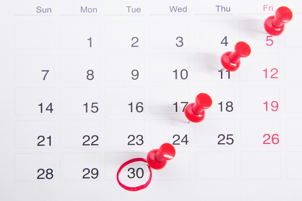 calendar with red pins in some of the days